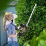 Frau schneidet Hecke mit Stiga Elektro-Heckenschere HT 106c. 55 cm Schnittlänge.