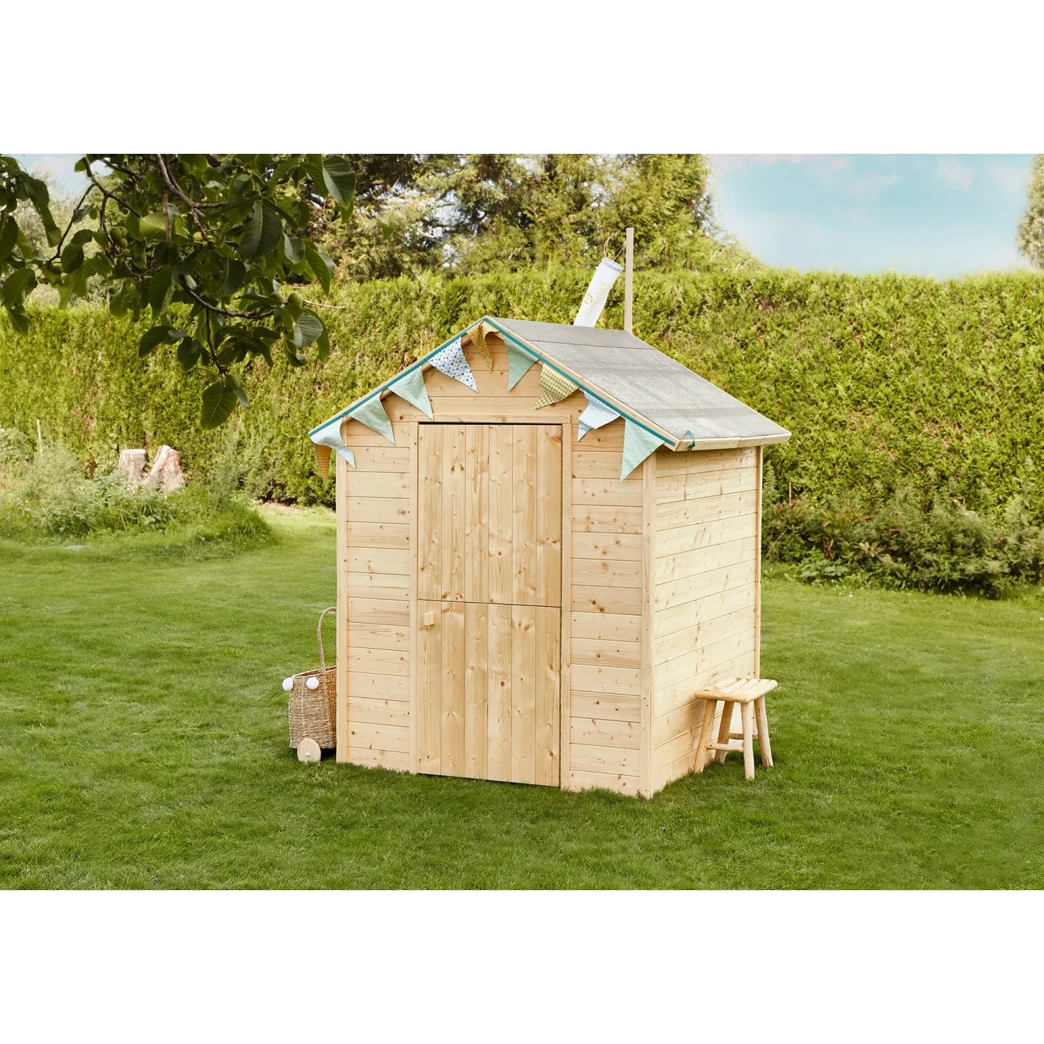 Soulet Kinderspielhaus Garance aus Holz, naturbelassen mit Windsack im Garten.