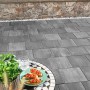 Verlegte Kann Pflastersteine Quadera in Vulkananthrazit, 30x30x6 cm, mit Tisch und Speisen im Außenbereich.