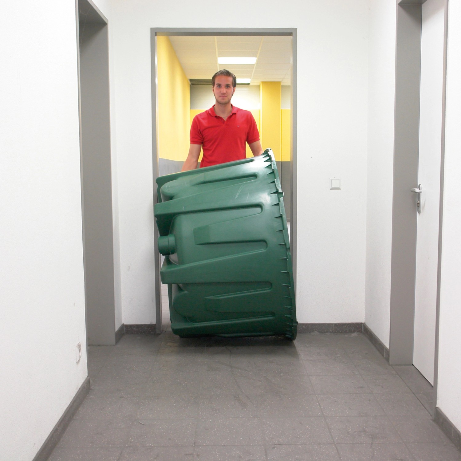 Grüne Garantia Zisterne Herkules 1600 l beim Transport durch einen Flur.