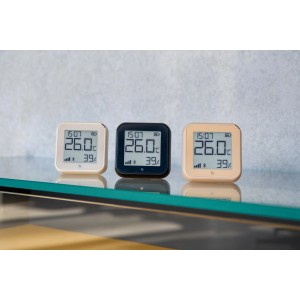 Shelly Temperatursensor Plus H&T G3 in Weiß, Schwarz und Beige auf Glasablage.