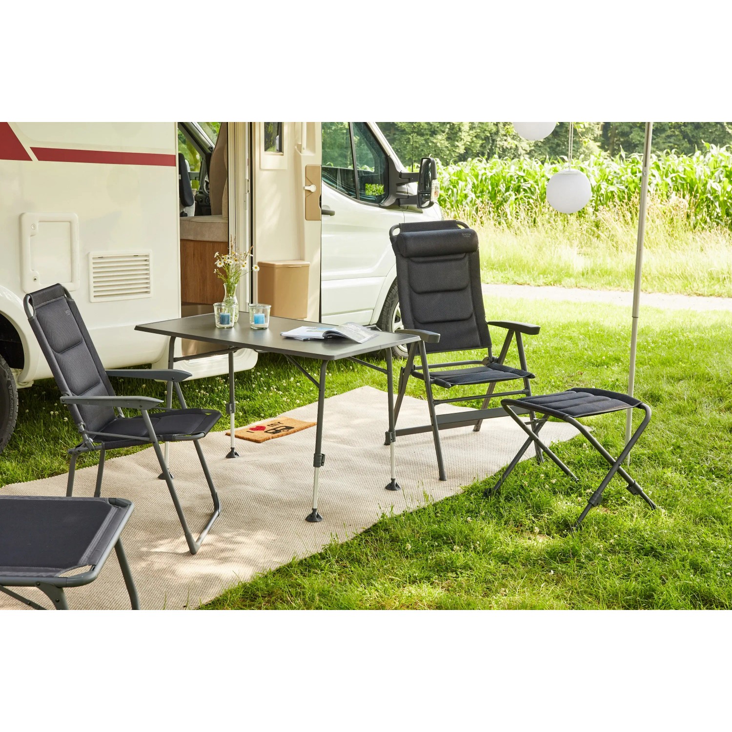 Siena Garden Campingsessel Premium, anthrazit, mit Tisch und Hocker vor Wohnmobil auf Rasen.