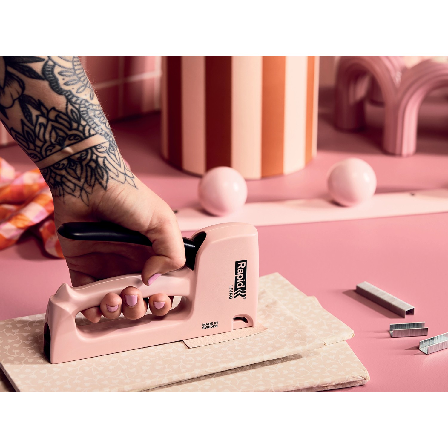 Rosa Rapid Handtacker beim Tackern von Stoff, mit Tackerklammern Typ 53/8 mm im Bild.