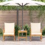 3-teiliges Garten-Lounge-Set aus Akazienholz mit cremefarbenen Kissen unter einem Sonnenschirm.