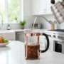 Bodum French Press Kaffeebereiter 1,0l mit Kupferrahmen in moderner Küche. Heißes Wasser wird auf Kaffeepulver gegossen.