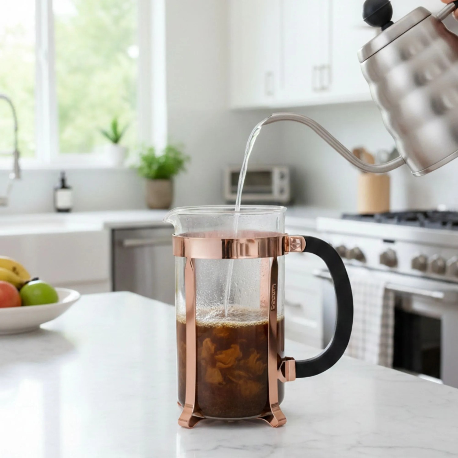 Bodum French Press Kaffeebereiter 1,0l mit Kupferrahmen in moderner Küche. Heißes Wasser wird auf Kaffeepulver gegossen.