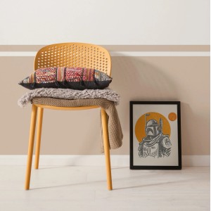 Wandbild Star Wars Boba Fett Illustration, 50x70 cm, beige, neben Stuhl mit Kissen.