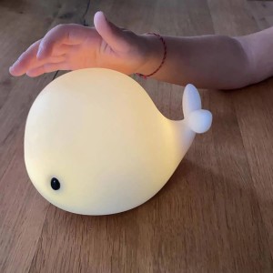 Leuchtendes LED-Nachtlicht in Walform, 15 cm, mit Hand, die es berührt. Nachtlampe für Kinder.