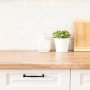 Küchenszene mit Contura Klarlack-behandelter Holzplatte, Schneidebrett und Pflanze.