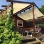 Peddy Shield Pergola Bausatz mit elfenbeinfarbenem Sonnensegel (420x140cm) auf einer Terrasse.