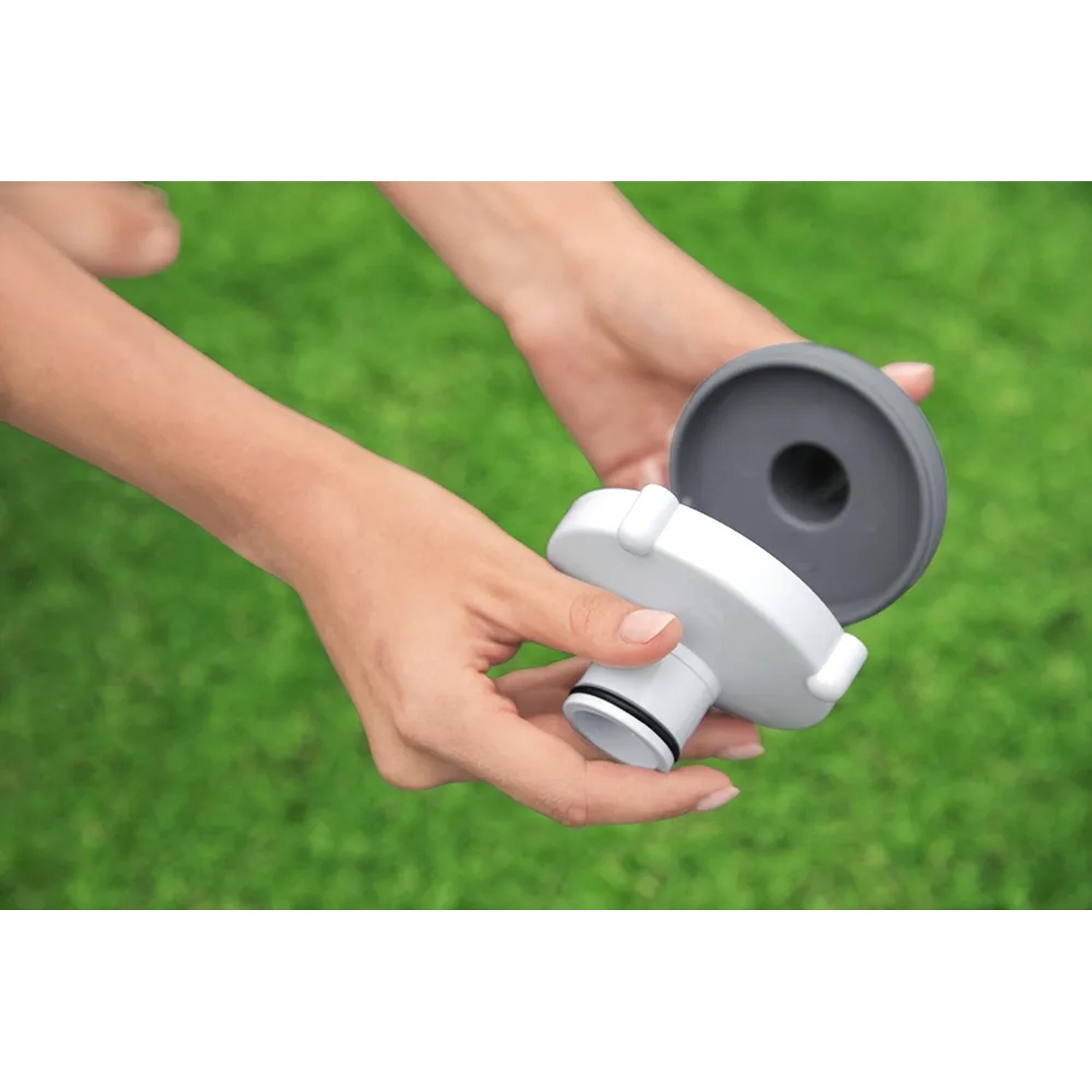 Detailaufnahme des Flowclear Poolsauger Aquasweeper Zubehörs in Händen vor grünem Hintergrund.