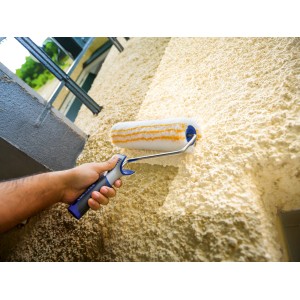 LUX Dispersionswalze 25 cm im Einsatz auf grober Wandstruktur. Farbwalze mit blau-grauem Griff.