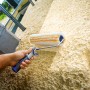 LUX Dispersionswalze 25 cm im Einsatz auf grober Wandstruktur. Farbwalze mit blau-grauem Griff.