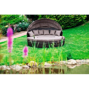 Braune Merxx Sonneninsel Riva aus Polyrattan mit Dach, Kissen und Auflagen im Garten.