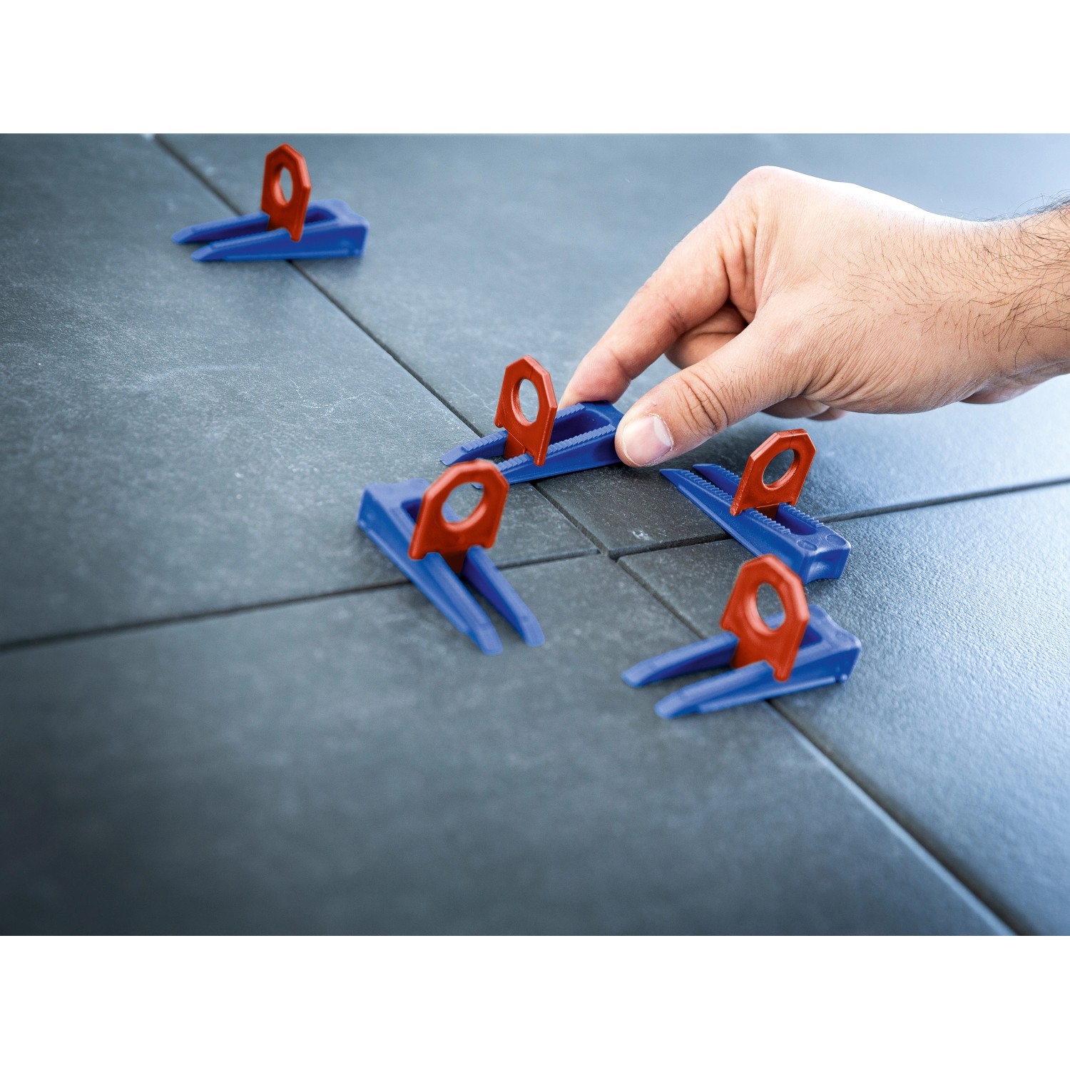 LUX Nivellierhilfe Startset mit Keilen und Clips (2 mm) im Einsatz zwischen Fliesen.