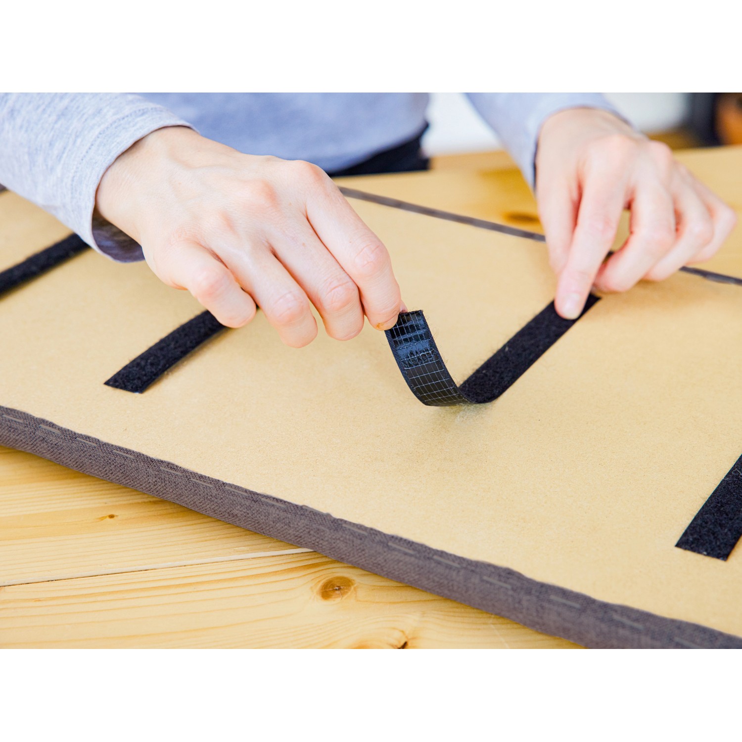 Montage des hellgrauen Wandkissens Bolster (120x15cm) mit Klettband.