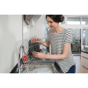 Frau reinigt Grillrost mit Vileda Glitzi Scheuerspirale (3er-Pack) in Spüle.