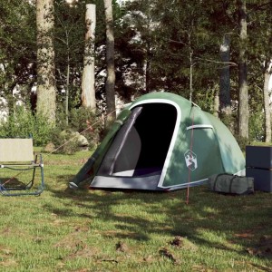 Grünes Furnicato Tunnelzelt für 2 Personen mit weißem Rand und Logo, aufgebaut im Wald. Campingstuhl daneben.
