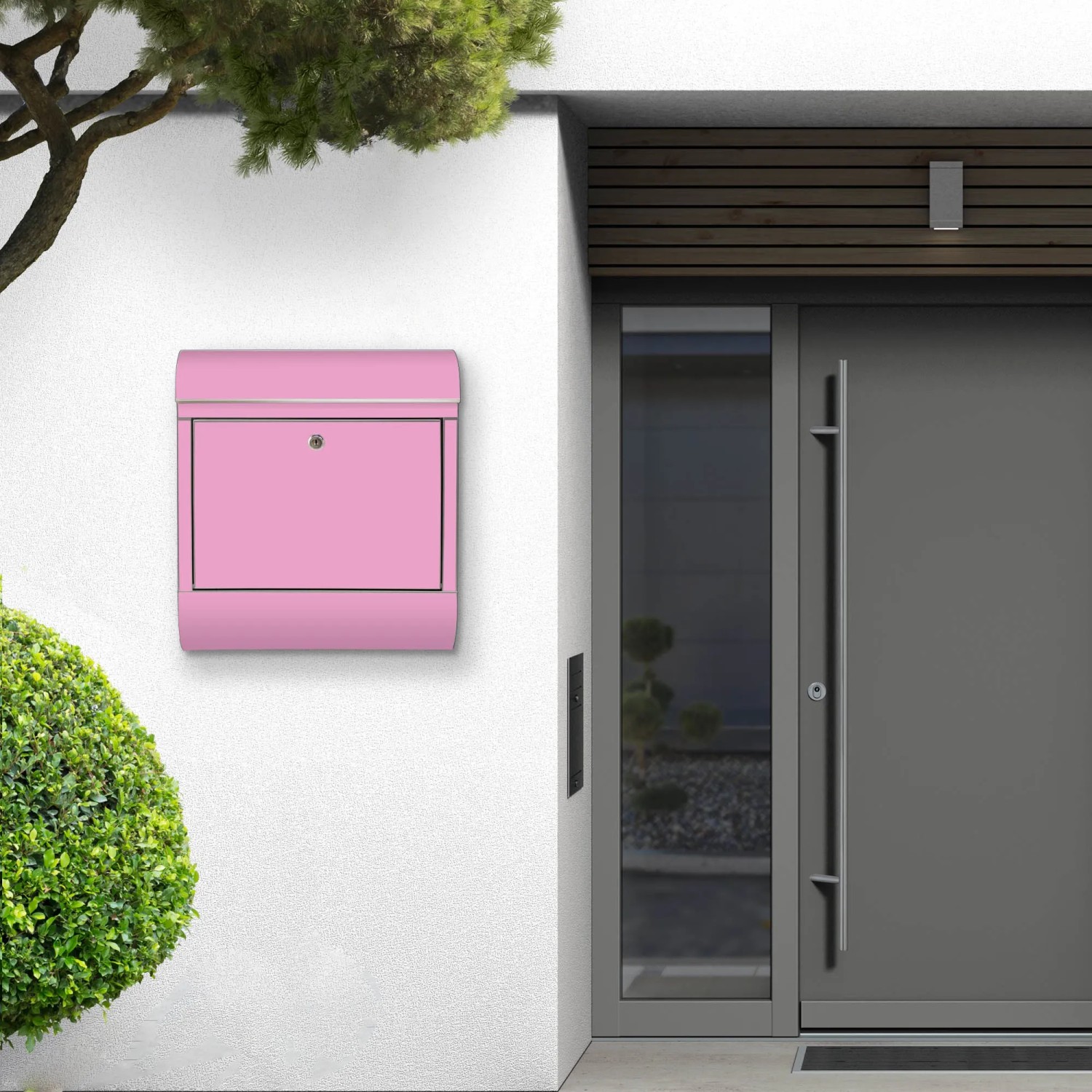 Pinker Banjado Edelstahl Briefkasten mit Rosen Motiv und Zeitungsfach an einer weißen Hauswand.
