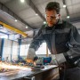 Mann schleift Metall mit dem Bosch Professional GWS 12-125 Winkelschleifer, Funken fliegen.