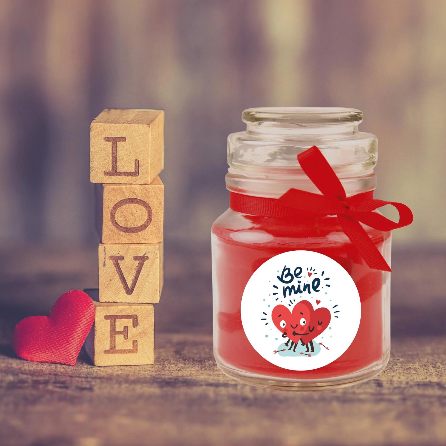 Duftkerze im Glas mit rotem Band und "Be Mine" Motiv, ideal zum Valentinstag.