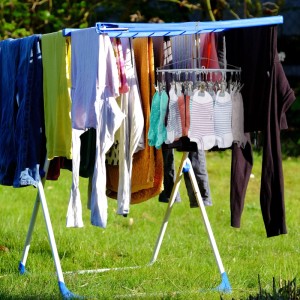 Grauer Relaxdays Sockentrockner mit 24 rutschfesten Clips hängt an blauem Wäscheständer im Garten, trocknet bunte Socken und Kleinteile.