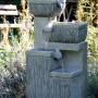 Großer, grauer Design-Gartenbrunnen mit 4 Stufen und LED-Beleuchtung. Dekoratives Wasserspiel für Garten und Terrasse.