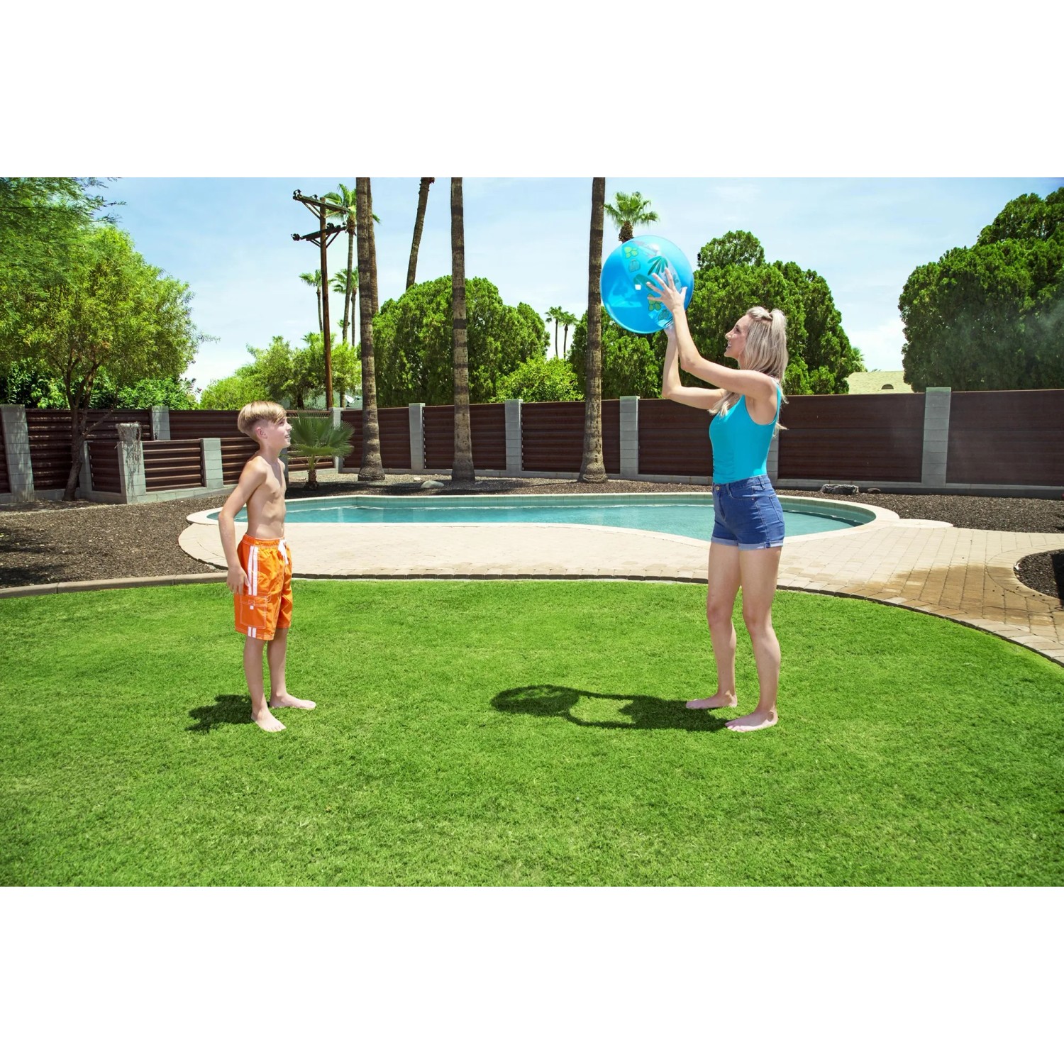 Frau wirft blauen Bestway Wasserball am Pool zu Kind im Garten.