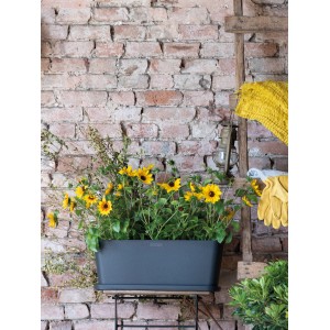 Anthrazitfarbener Deroma Pflanzkasten Origin 50 cm mit Sonnenblumen auf einem Tisch vor einer Ziegelwand.