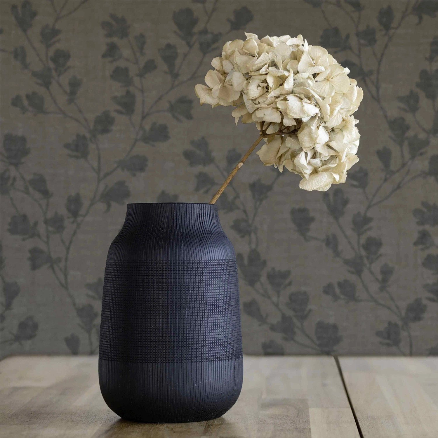 Tadessi Vliestapete Floral M1-No.3995 in Schwarz mit elegantem Blumenmuster, im Raum mit Vase.