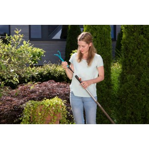 Frau montiert Gardena combisystem-Kleingrubber an Stiel im Garten.