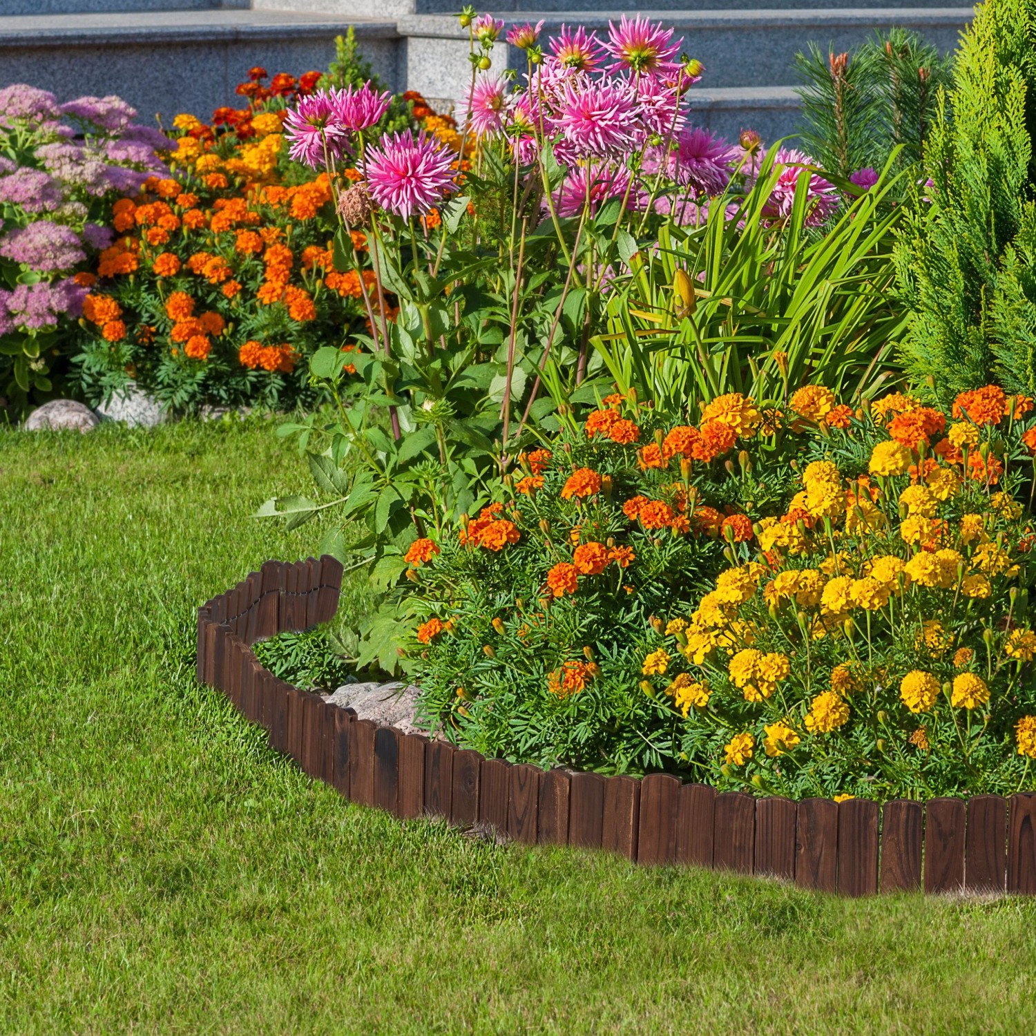 Dunkelbraune, flexible Beeteinfassung aus Tannenholz trennt Rasen von Blumenbeet mit bunten Blüten im Garten.
