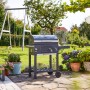 Jamestown Holzkohlegrillwagen Jaxon im Garten mit Seitentisch und Ablage.