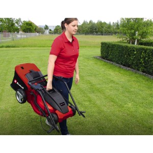 Frau trägt roten Einhell Elektro-Rasenmäher GC-EM 1700/42 über eine grüne Wiese.