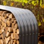 Anthrazitfarbenes Westmann Kaminholzregal aus Stahl, gefüllt mit Holzscheiten.
