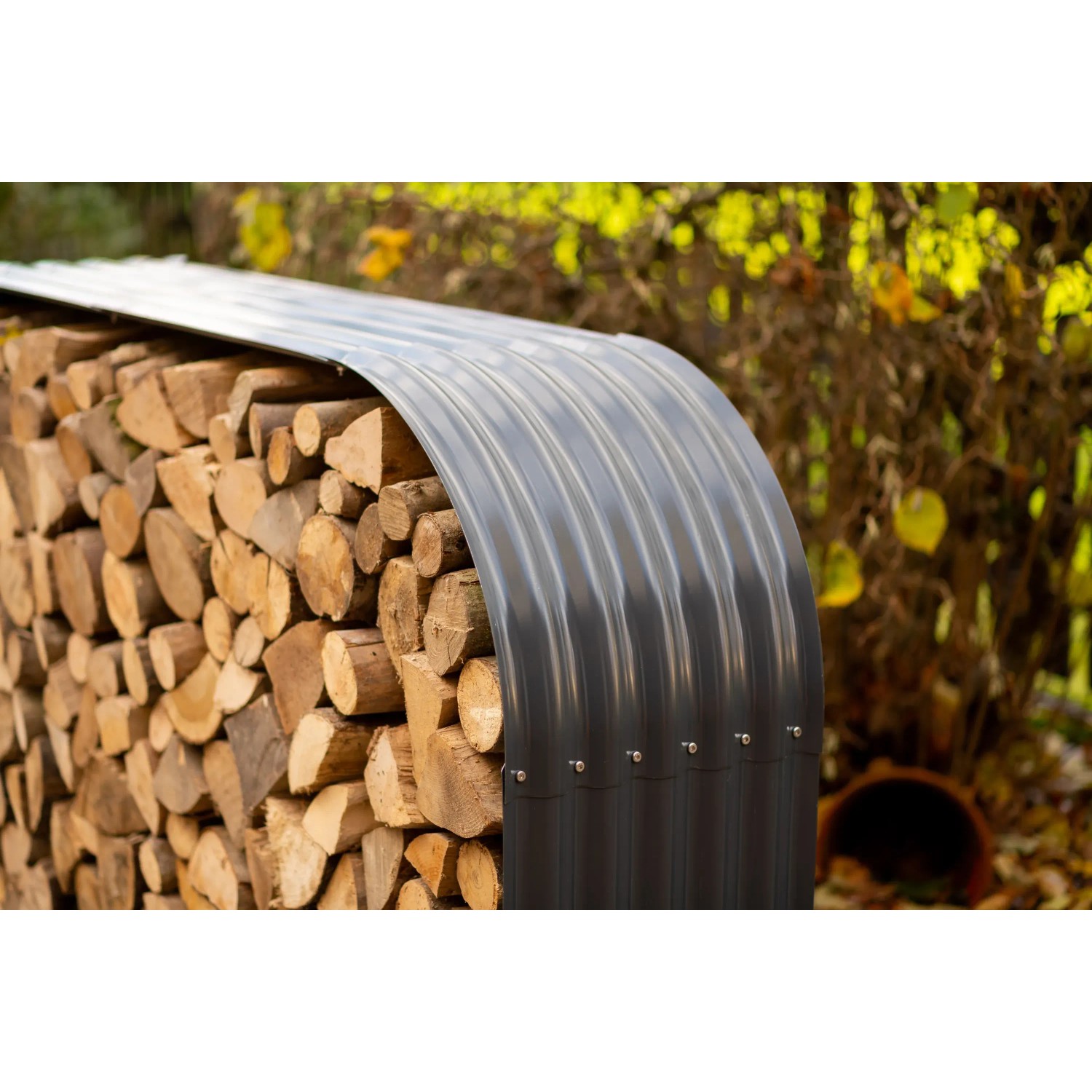 Anthrazitfarbenes Westmann Kaminholzregal aus Stahl, gefüllt mit Holzscheiten.