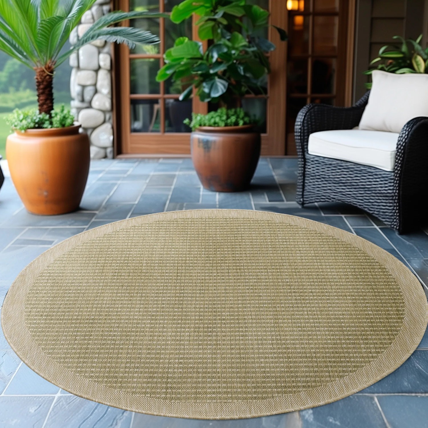 Runder, grüner Outdoor-Teppich Giza von Ayyildiz, 200x200 cm, auf einer Terrasse.