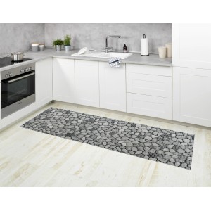 Mehrfarbige Wenko Badematte Sassi (65x200 cm) im Stein-Design als Küchenläufer vor weißer Küchenzeile.