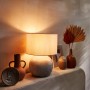 Dekorative orange Vase Ancient Secrets, 20 cm, auf einem Tisch mit Lampe und Deko.