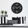 Moderne schwarze Wanduhr (Ø 38,5 cm) von Wall-Art über einem Bett mit schwarz-weißem Muster.