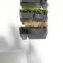 Ecopots Manhattan Wall Hängetöpfe in Dunkelgrau, bepflanzt, an einer weißen Wand.