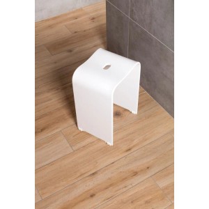 Mattweißer Acryl Badhocker für Dusche und Bad. Freistehend, modern, auf Holzboden vor grauen Fliesen.