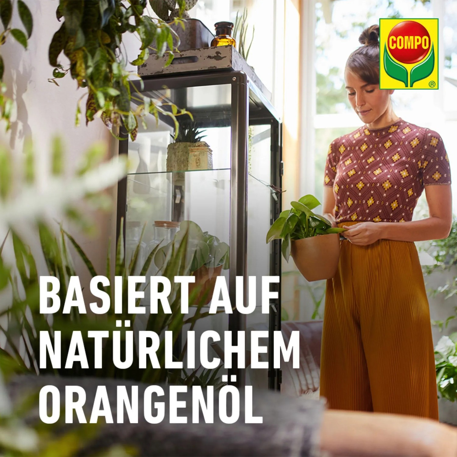 Frau mit Zimmerpflanze, Compo Insektenmittel Prev-AM im Hintergrund. Natürliches Orangenöl.
