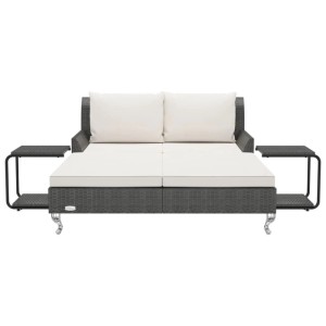 Doppelte Sonnenliege aus Rattan in Schwarz mit cremeweißen Kissen und Beistelltischen.