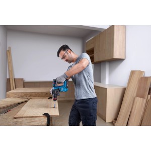 Mann bohrt mit Bosch Professional Akku-Bohrhammer GBH 18V-18 X ein Loch in ein Holzbrett.