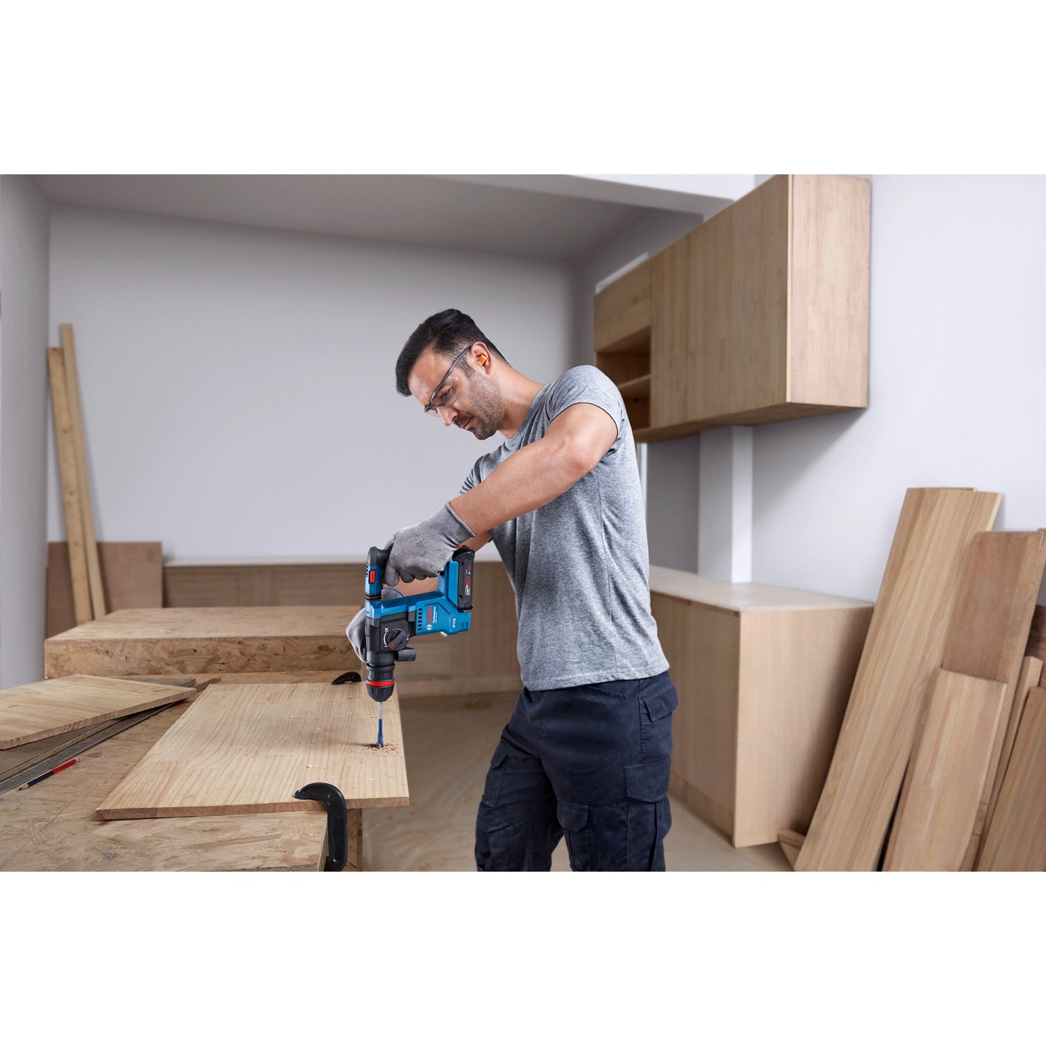 Mann bohrt mit Bosch Professional Akku-Bohrhammer GBH 18V-18 X ein Loch in ein Holzbrett.