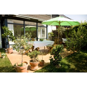 Terrasse mit Classico Smart Natur Terrassendielen aus Bambus, Tisch, Stühlen und Sonnenschirm.