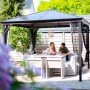 Sojag Pavillon Verona, 298x298 cm, Anthrazit. Paar sitzt entspannt im Garten unter dem Pavillon.