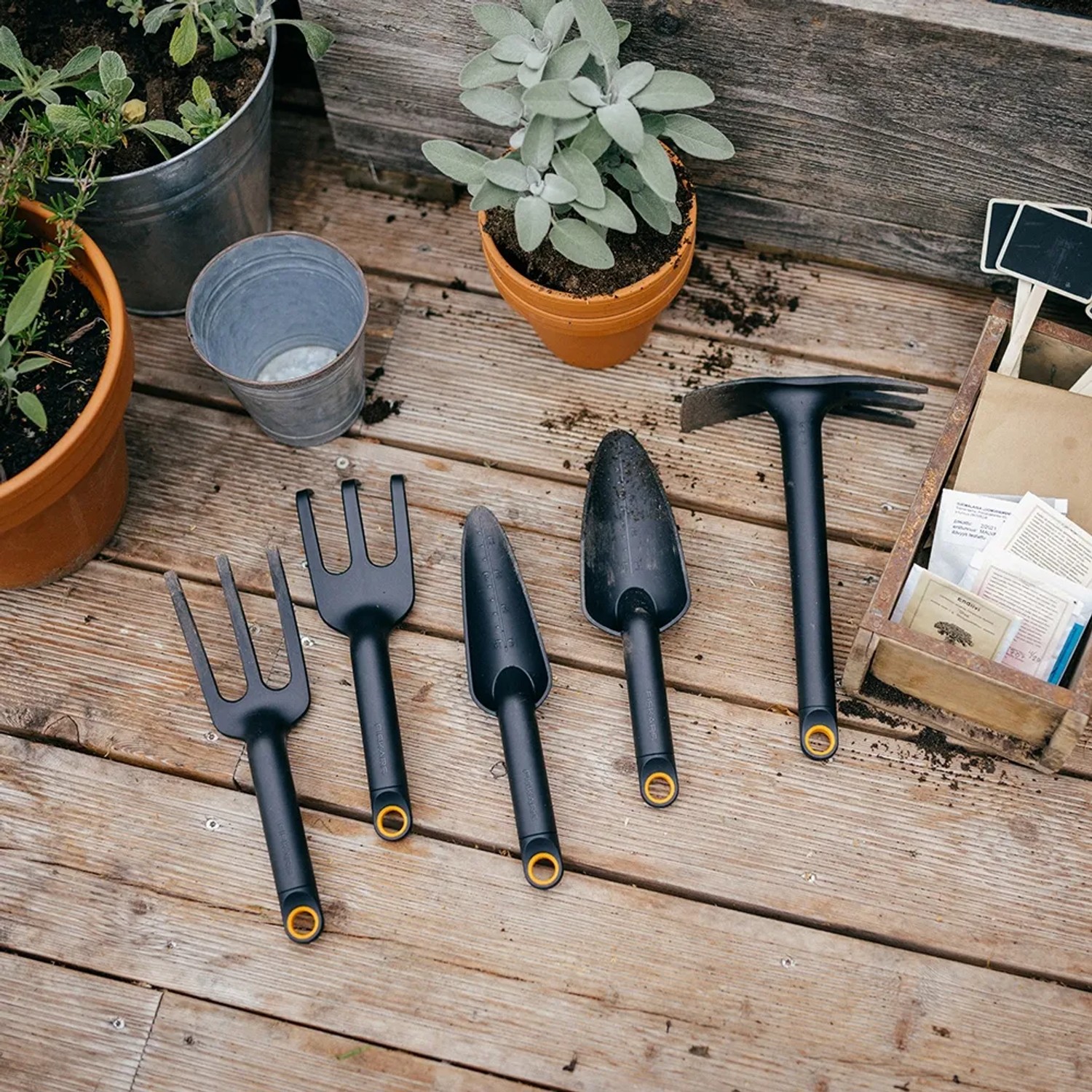 Fiskars Solid Gartengeräte Set: Blumenkelle, Grubber und Gabel auf Holzterrasse.