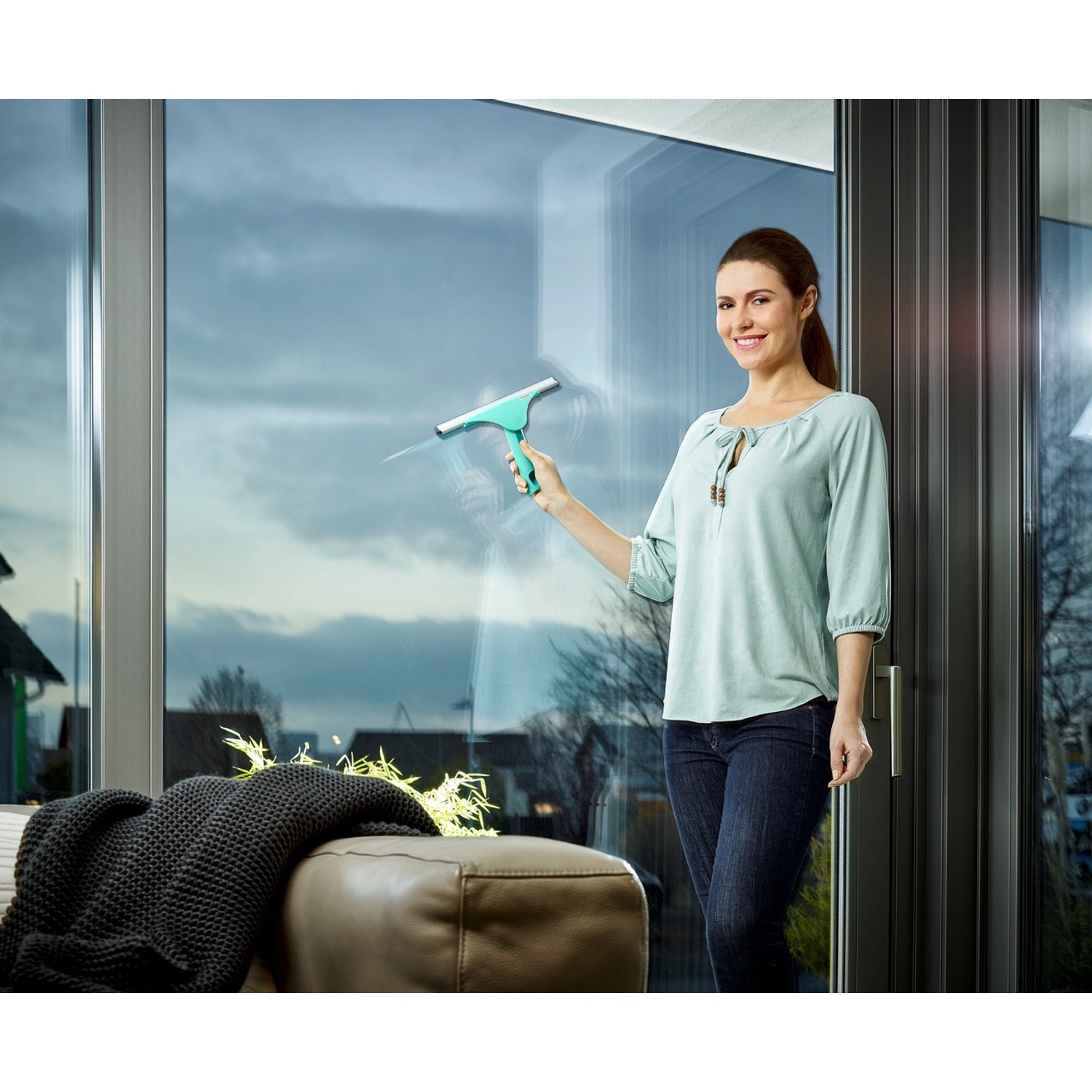 Frau reinigt Fenster mit Leifheit Fensterabzieher Window Slider M, Reinigungsgerät mit beweglichem Gelenk.